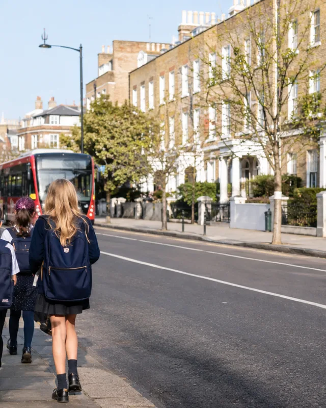 Niños caminando a la escuela por una calle residencial de Londres bajo un cielo despejado