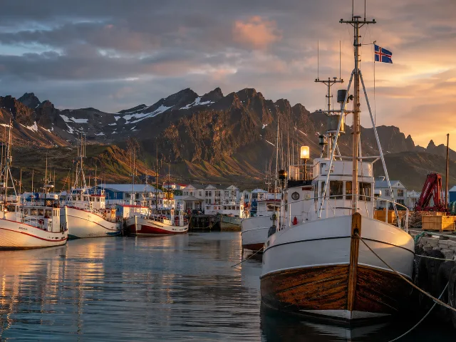 Puerto pesquero tradicional en Islandia con la costa volcánica al fondo, al atardecer