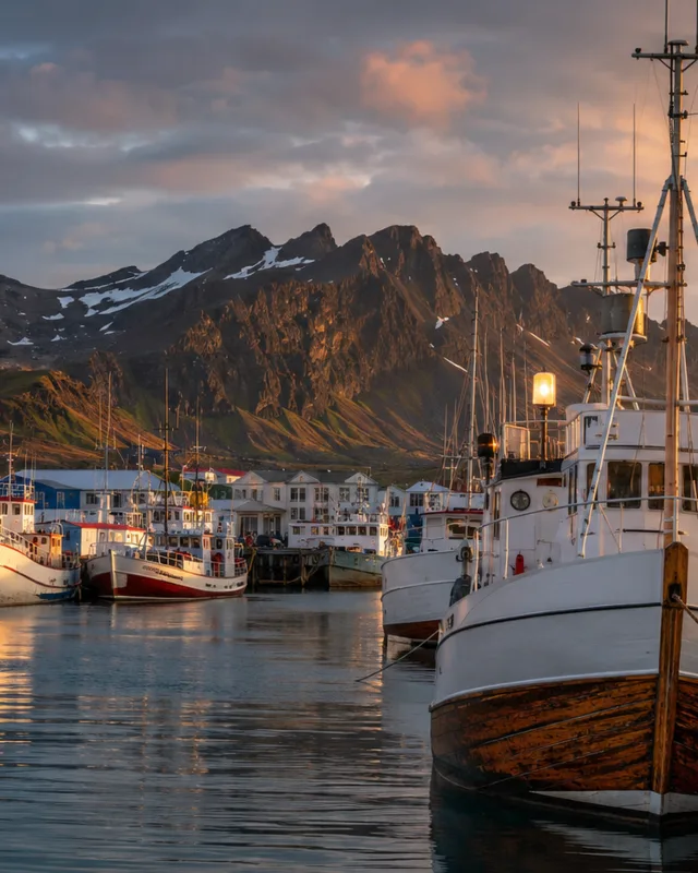 Puerto pesquero tradicional en Islandia con la costa volcánica al fondo, al atardecer