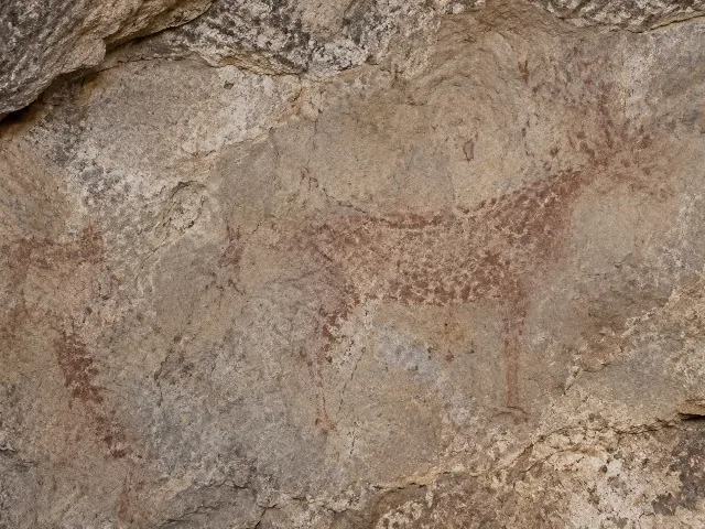 Fotografía editorial de una pared de roca con pigmentos de arte rupestre realzados mediante procesamiento digital de colores falsos